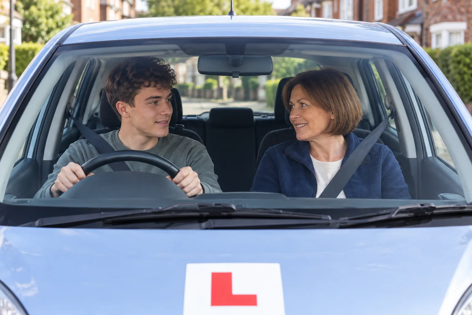 A driving instructor talking with an adult learner in a parked right-hand-drive car