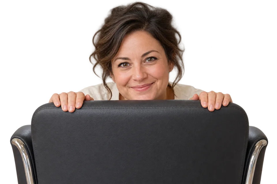 A smiling salon owner peeking over the back of a salon chair